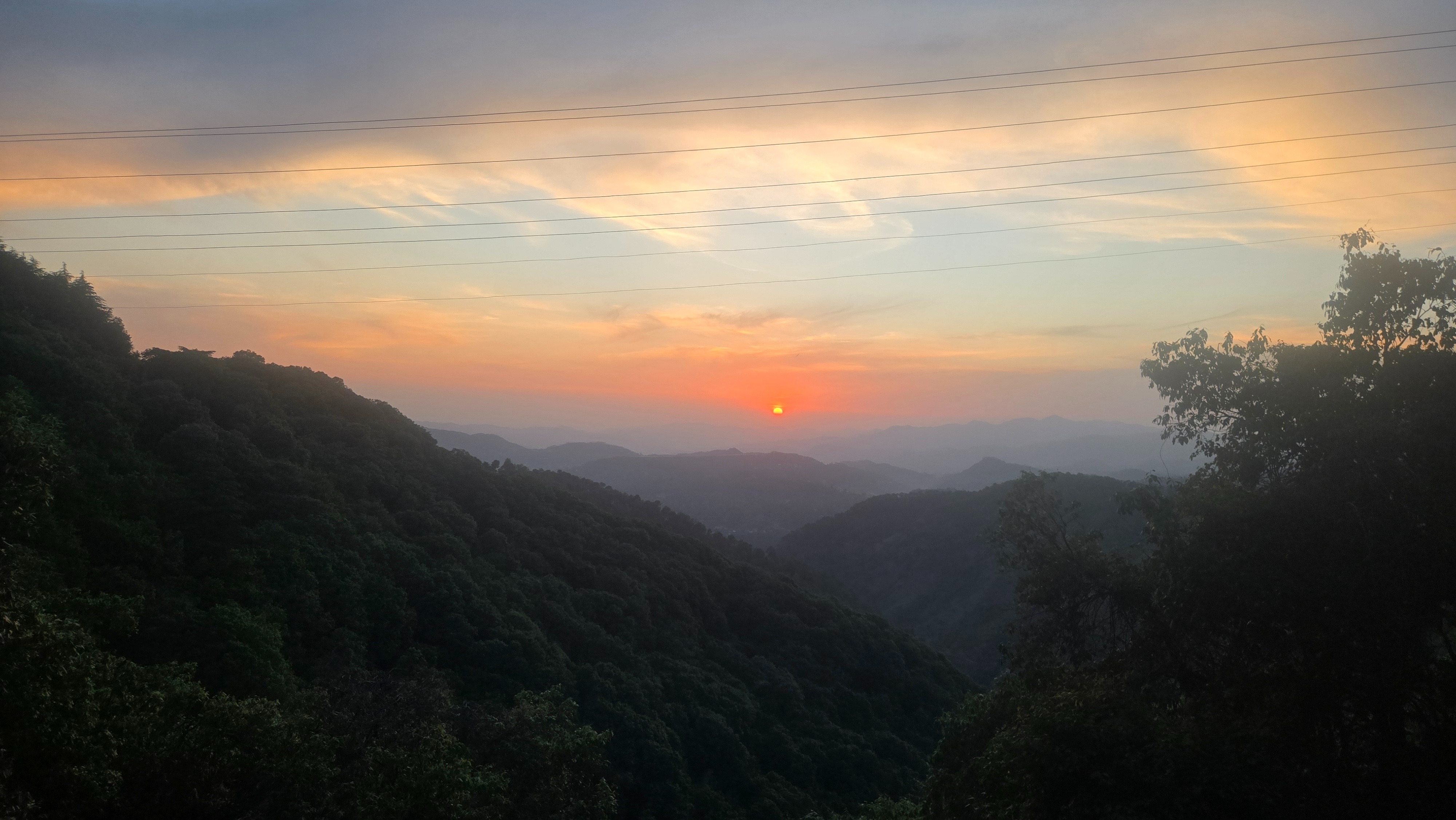 Serene mountain sunset with lush greenery in the foreground.